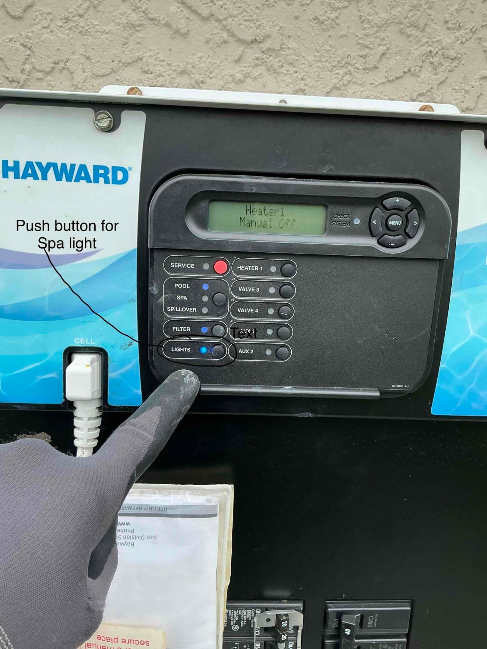Hayward pool control panel displaying spa light push button and multiple valve/heater controls with technician pointing to labeled features.