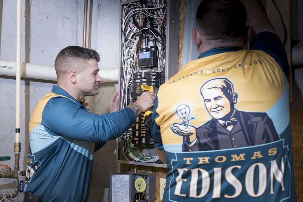 Two Thomas Edison Electric electricians working on an electrical panel